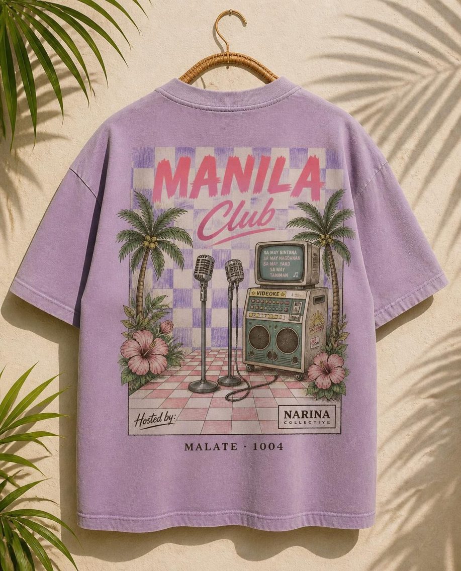 Lilac oversized tee with the Manila Club check print, hanging on a rattan hanger